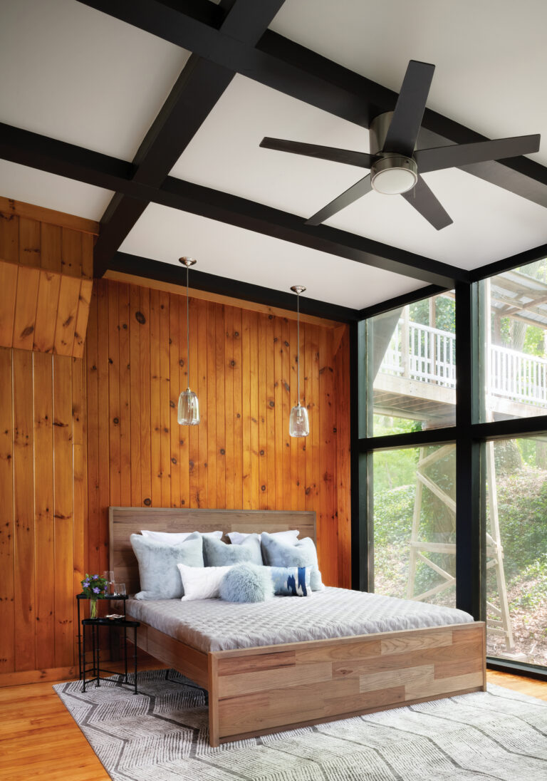 A primary bedroom embraces the home’s mid-century provenance with black-painted beams and a wall of natural lapped wood.