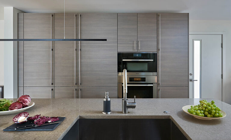 Galley-style kitchen remodel featuring an island with a built-in sink providing clearance for multiple cooks and plenty of convenient storage. ARCHITECTURE: CARNEMARK design + build PHOTOGRAPHY: Anice Hoachlander