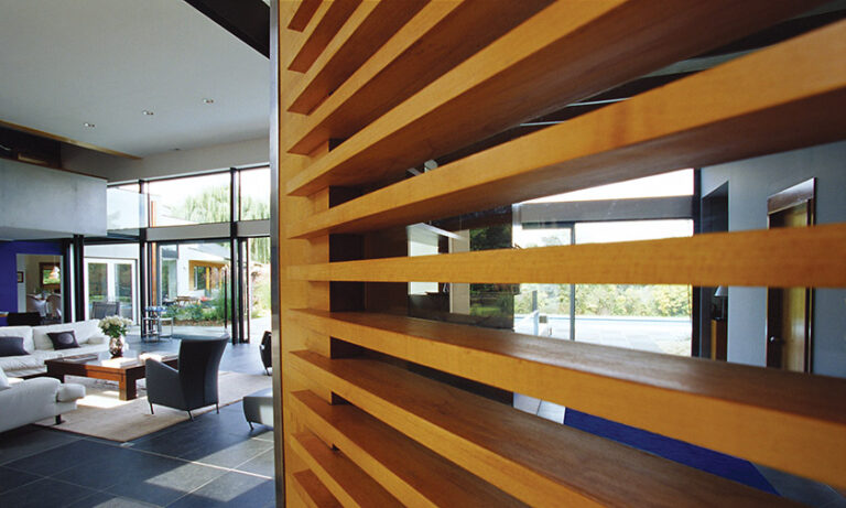 In a new Potomac residence, a custom maple door leads into the living room, where a continuous, 50-foot glass wall opens towards the terrace, pool and landscape beyond. INTERIOR DESIGN: ColePrévost PHOTOGRAPHY: Timothy Bell