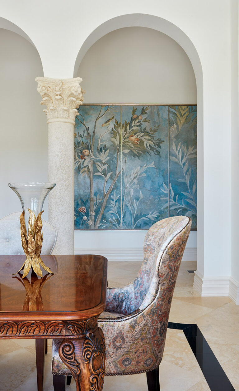 The dining room showcases a fresco painting on the wall; it complements the chair fabric and a gold objet d’art on the table in a similar leaf pattern. INTERIOR DESIGN: Interior Concepts, Inc. PHOTOGRAPHY: Brantley Photography