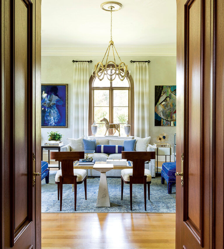 In a condo’s living room, a geometric metallic wall covering is the backdrop to hair-on-hide chairs with faux-bone frames and an acrylic coffee table that accents the textured rug. INTERIOR DESIGN: Lorna Gross Interior Design PHOTOGRAPHY: Angie Seckinger