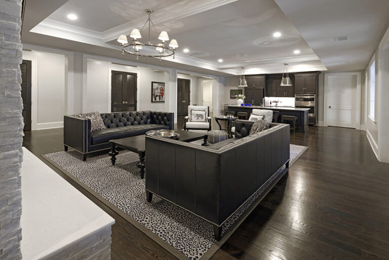Classic and tailored this lower level family room is a place to gather and entertain. Custom bar and cabinetry by Artisan Builders. Indoor-outdoor custom carpet by Carpet Creations. The seating arrangement creates a comfortable setting around the fireplace. INTERIOR DESIGN: MAX Interiors PHOTOGRAPHY: Bob Narod