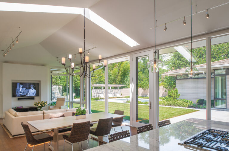 The home maximizes natural light via expansive windows and large doors that facilitate connections to a garden courtyard.