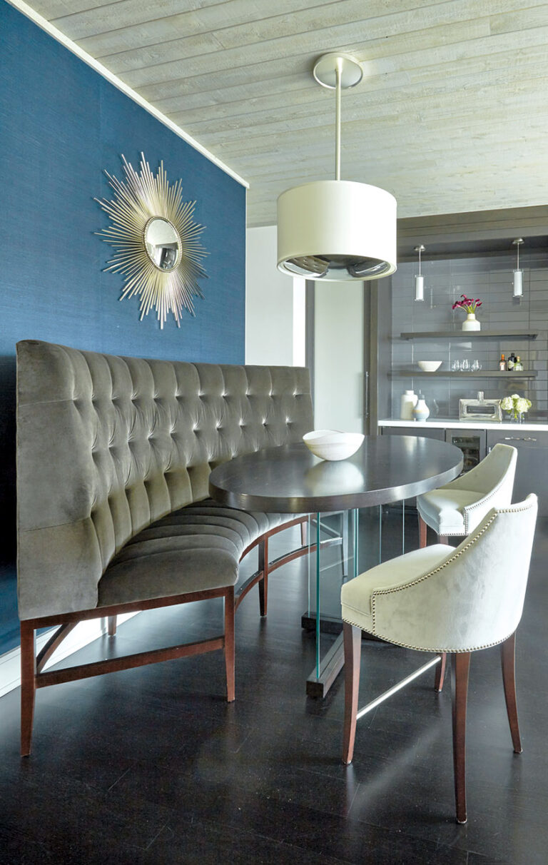 A coastal retreat with gray-stained wood ceilings features a curved, bar-height banquette that overlooks the water. INTERIOR DESIGN: Sroka Design Incorporated PHOTOGRAPHY: Timothy Bell