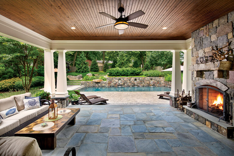 A covered lanai complete with its own fireplace overlooks a beautiful pool where spillways animate a granite-and-Pennsylvania-bluestone wall. LANDSCAPE ARCHITECTURE: Surrounds Landscape Architecture + Construction PHOTOGRAPHY: Morgan Howarth