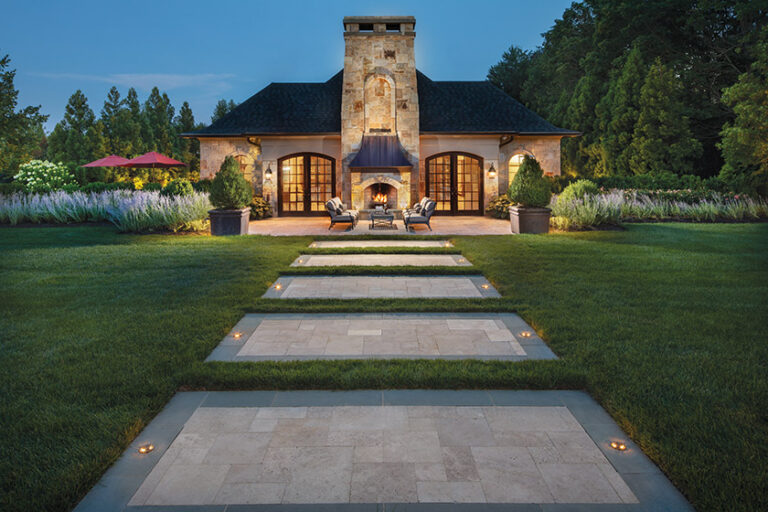 Lawn steppers, made of Pennsylvania bluestone and travertine, lead to a custom pool house featuring a quartzite-stone fireplace and a copper hood. LANDSCAPE ARCHITECTURE: Surrounds Landscape Architecture + Construction PHOTOGRAPHY: Morgan Howarth