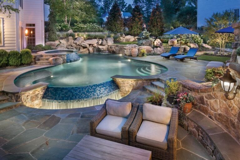 A freeform pool and raised spa boast spillways clad in mosaic tile set into grade with a raised bond beam wall and boulder water feature. LANDSCAPE ARCHITECTURE: Surrounds Landscape Architecture + Construction PHOTOGRAPHY: Morgan Howarth