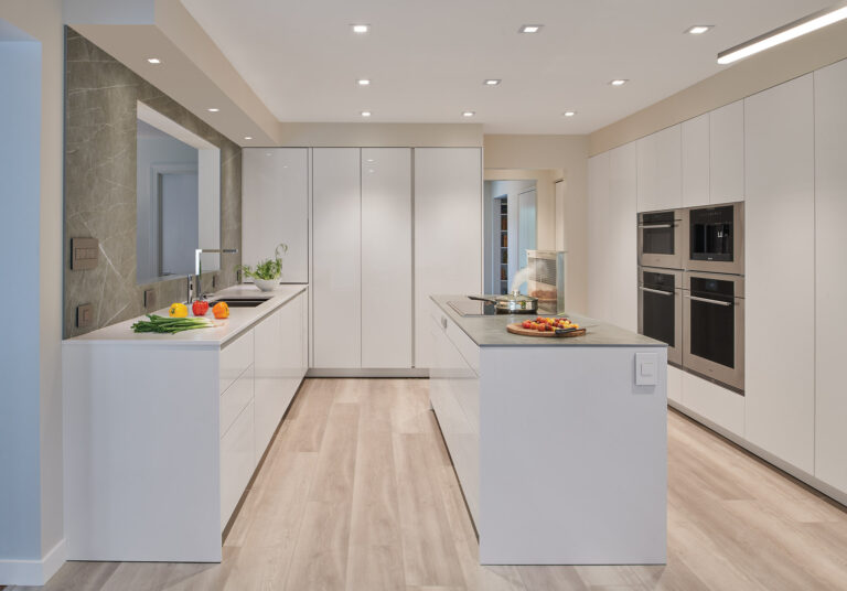A minimalist contemporary kitchen features abundant storage behind push-to-open, matte-white lacquer cabinetry. ARCHITECTURE: CARNEMRK design. + build PHOTOGRAPHY: Anice Hoachlander