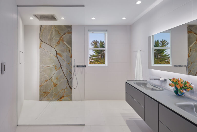 A shower slab of veined quartzite pops against a bright white backdrop of large-format, slip-resistant porcelain tiles that envelop a bathroom. ARCHITECTURE: CARNEMRK design. + build PHOTOGRAPHY: Anice Hoachlander