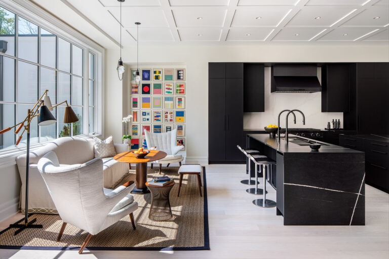 A gracious seating area creates a welcoming space for gathering with friends and family in a contemporary chef’s kitchen, which features matte-black cabinetry, designated work zones, double islands and wide aisles. ARCHITECTURE: CAR-NEMRK design. + build PHOTOGRAPHY: Ron Blunt