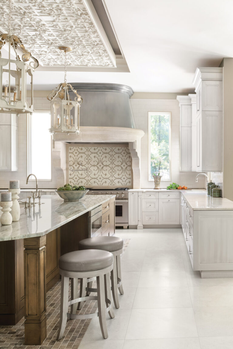 In the kitchen, a pewter-and-limestone hood with an elegant mosaic-tile backsplash creates a timeless focal point. INTERIOR DESIGN: Interior Concepts, Inc. PHOTOGRAPHY: Stylish Productions