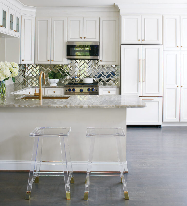 In an Arlington townhouse, a stunning beveled-mirror backsplash expands the feel of a kitchen, while gold metallic hardware, acrylic stools and exotic stone countertops add glamour. INTERIOR DESIGN: Lorna Gross Interior Design PHOTOGRAPHY: Rachel Heacox