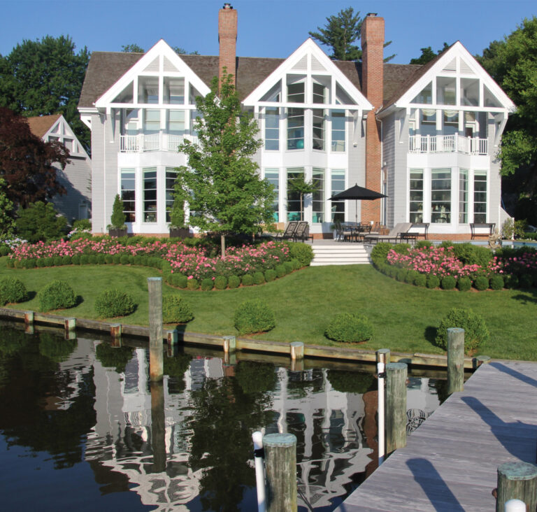 A bold landscape as seen from the dock with sweeping masses of drift roses and boxwood. LANDSCAPE ARCHITECTURE: Walnut Hill Landscape Company