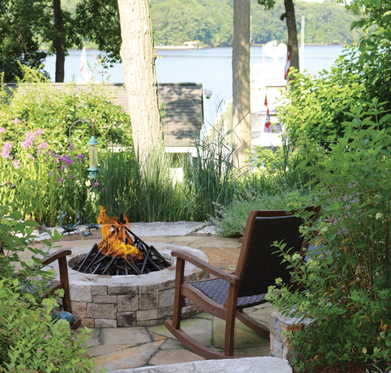 A custom masonry fire pit sits within a lush landscape overlooking the Severn River. LANDSCAPE ARCHITECTURE: Walnut Hill Landscape Company PHOTOGRAPHY: David Burroughs