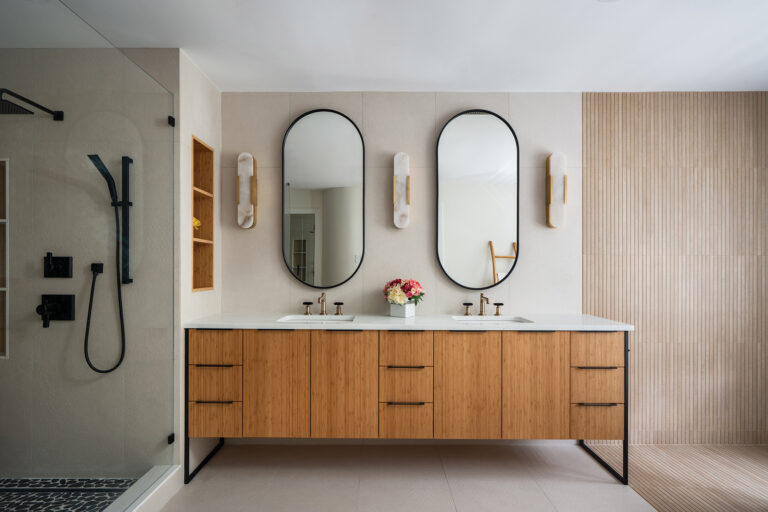 A Zen-inspired design prevails in a Bethesda bath featuring a bamboo double vanity with a quartz countertop. A glass-enclosed shower is outfitted with matte-black fixtures.