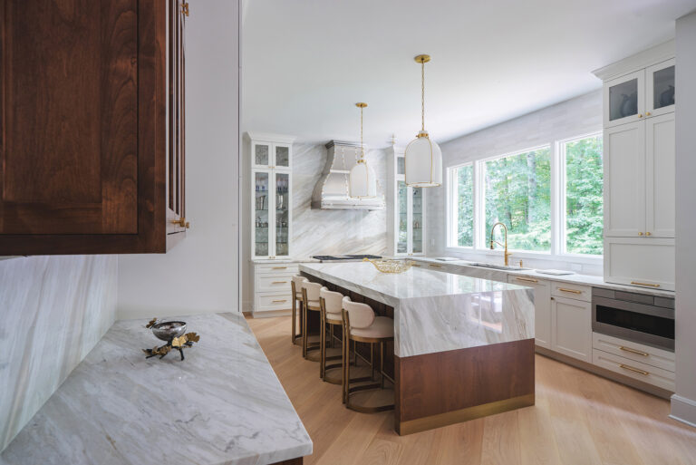 A French-inspired steel range hood is a focal point in a traditional Bethesda kitchen with quartzite surfaces and warm, wood accents.