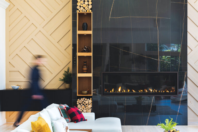 A dramatic fireplace wall clad in black stone with striking natural veining created a bold focal point in a Potomac home.